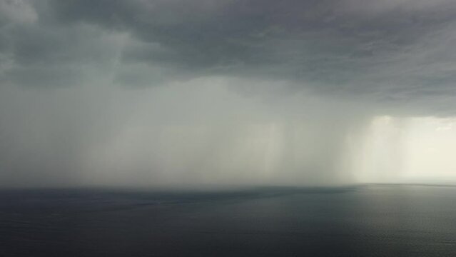 Aerial view footage of rain clouds over sea ocean Black clouds in bad weather day over sea surface High angle view nature view. Apocalypse. Storm Large freight dark gloomy rain clouds over a calm sea.