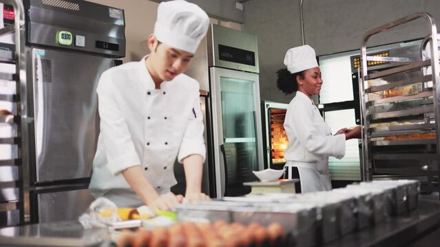 Asian young man chefs  baker in a chef dress and hat, cooking together in kitchen.Team of professional cooks in uniform preparing meals for a restaurant.
