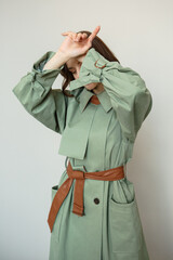 A model in a green coat with a brown leather belt. Clothing advertising