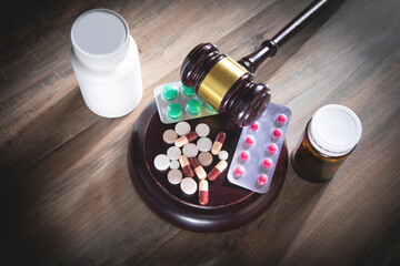 Judge gavel with pills on the wooden table.