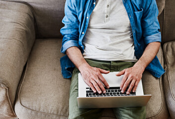 Online, all the time. High angle shot of an unidentifiable bachelor using his laptop while relaxing...