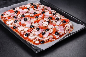 Raw homemade Pizza and Ingredients on black concrete table, top view