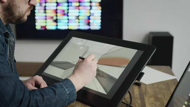 An experienced interior designer creates style for modern apartments. A man works with a graphics editor using an interactive tablet.
