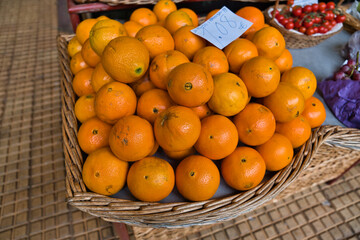 A lot of fresh Orange fruits in big wicker basket on the traditional fruits market in Funchal, Madeira Island, Portugal