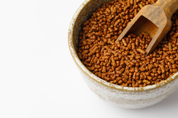 Buckwheat tea in a bowl with wooden spoon on white background. Healthy ku qiao or soba tea, buckwheat tea seeds. Copy space.