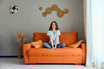 Obraz premium woman on the orange couch in the rest room posing apartments