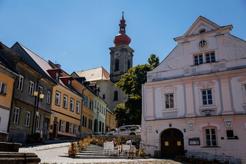 Becov nad Teplou, West Bohemia, Czech Republic, 14 August 2021: colorful buildings in historic center in medieval city, baroque Church of St. Jiri with bell clock tower near city hall at summer day