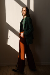 A model girl standing in the rays of the sun. the girl in the reflection of light from the window