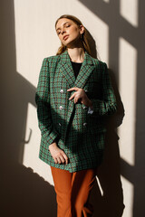 A model girl standing in the rays of the sun. the girl in the reflection of light from the window