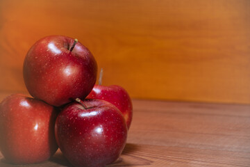 three red apples with raindrops on a wooden background with a place for text: rustic food, harvest gardening, ingredients for a healthy snack, soft focus, crop image
