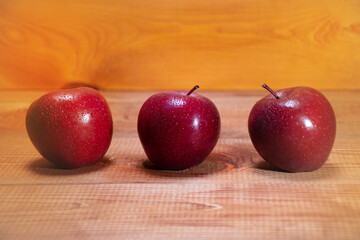 Side view three red apples on a wooden background with a place for text: rustic food, harvest...