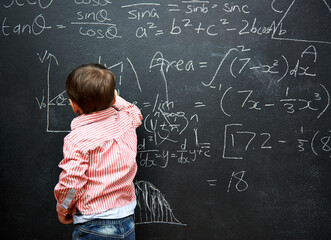 Mastering math. Shot of a young boy with a blackboard full of math equations.