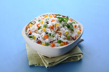 Indian veg biryani, veg pulav, Indian vegetable pulav, Biriyani, vegetable Biriyani served in a ceramic bowl on blue background