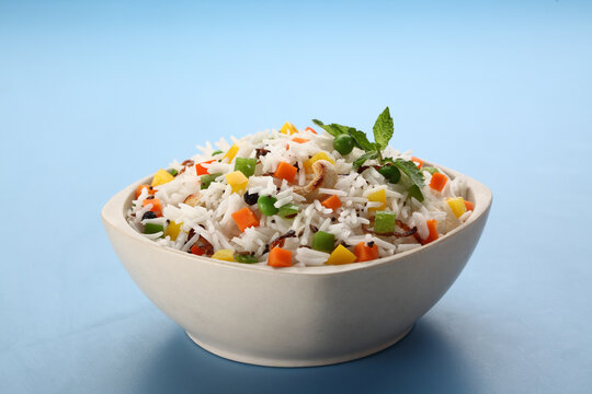 Indian veg biryani, veg pulav, Indian vegetable pulav, Biriyani, vegetable Biriyani served in a ceramic bowl on blue background