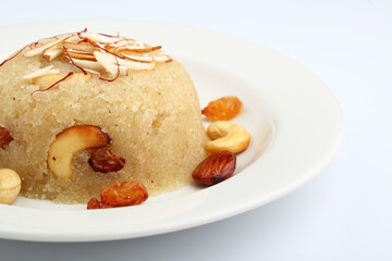 Indian gujrati or maharashtrian or south indian sweet dish SUJI Halwa or sheera or KESARI, famous sweet food in india, also known as halwa, served in white ceramic plate, garnished with dry fruits