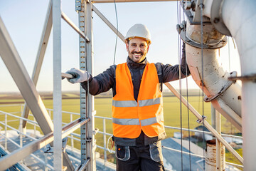 A heavy industry worker on height smiling at the camera.