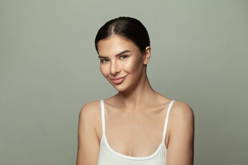 Young woman posing over grey wall background and smiling