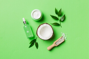 Coconut with jars of coconut oil and cosmetic cream on colored background. Top view. Free space for your text. Natural spa coconut cosmetics and organic treatment concept Coconut Spa composition