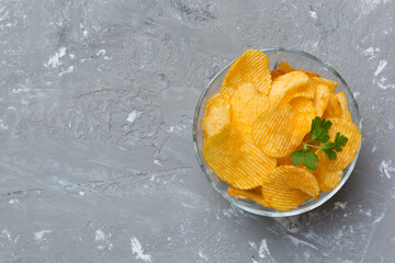 Potato chips on bowl with napkin on colored background. Delicious crispy potato chips in bowl. Space for text. Top view