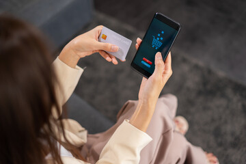 Asian beautiful businesswoman make payment by credit card via mobile phone for shopping online, selective focus at payment via mobile phone. Young woman shopping online in home office