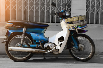 An old or classic market motorcycle is parked on the side of the road with sunlight in the background in an old building. Retro and vintage vehicle concept.
