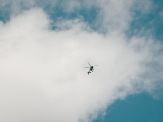 A small helicopter in a cloudy sky. Private flights, transportation of tourists.
