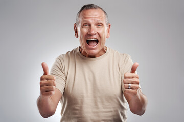 It cant get better than a double thumbs up. Shot of a handsome mature man standing against a grey...