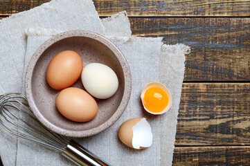Fresh raw chicken eggs in a bowl on wooden background, top view. Cooking omelet, pastry, sauce.