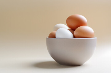 Different farm eggs in a bowl on a pastel background. Healthy food concept, organic food