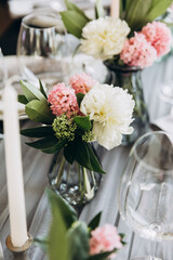 Wedding. Banquet. Decor. Festive tables are decorated with fabric, compositions of flowers and greenery in glass vases, there are candles, glasses, plates and cutlery on the tables
