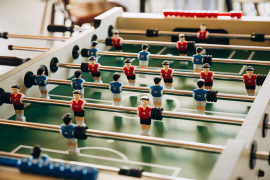 A game. Table football, figurines of football players in red and blue on a green stadium