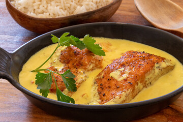 salmon steak in coconut milk with rice on a table