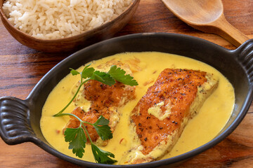 salmon steak in coconut milk with rice on a table