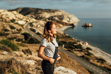 young woman 20-25 years of European appearance stands in the mountains on a background of sea and mountains