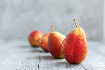Ripe red pears lined up in a row on wooden table