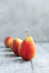 Ripe red pears lined up in a row on wooden table