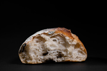Olive French baguette bread cross section view with isolated black background.