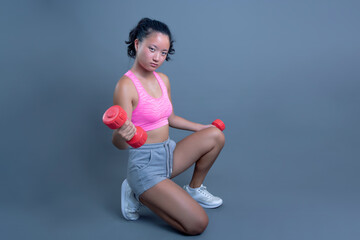 young woman of asian ethnicity posing with weights and sportswear