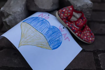 Fototapeten children's shoes and the flag of Ukraine, the war © Angelov