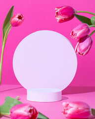 Pink podium for product display on pink with tulips flowers in hard light