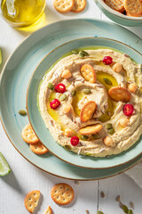 Homemade and vegan hummus with pumpkin seeds and crackers.