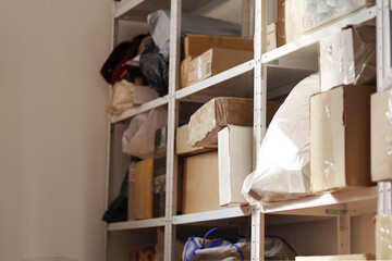 Storage of boxes and crates on shelves. Warehouse with shelving in a garage or utility room. Blurred wall background
