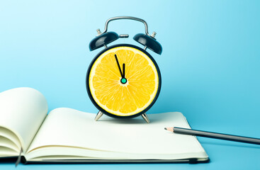 Alarm clock with citrus fruit concept. Lemon or orange and clock on empty color background....