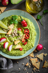 Tasty and homemade guacamole with crackers, herbs and sunflower seeds.