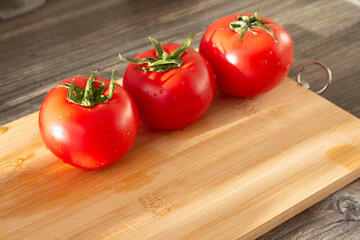 ripe tomatoes in the sun are lying on a cutting board, diagonal