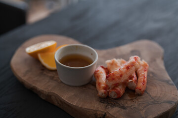 Crab served with sauce and sweet lemon on olive wood board