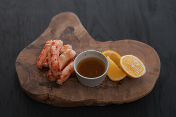 Crab served with sauce and sweet lemon on olive wood board