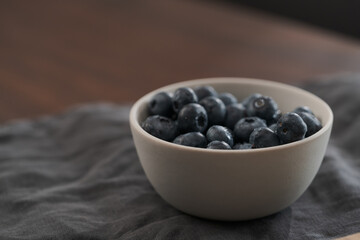 Fresh washed blueberries in white bowl on wood table