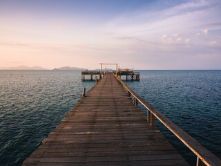 Scenic view of peaceful long straight wooden pier over blue water in evening before sunset. Koh Mak Island, Trat Province, Thailand. Minimal background.