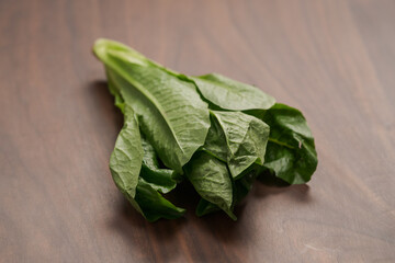 Small romaine lettuce leaves on walnut table